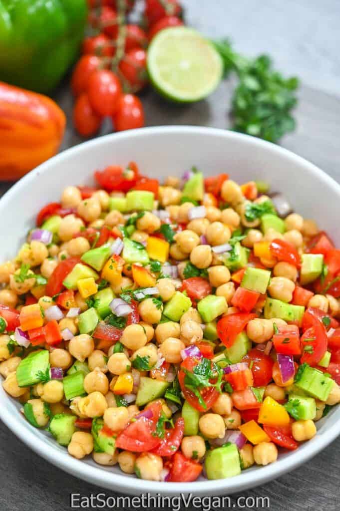 Easy Chickpea Salad in a white bowl with veggies in the background