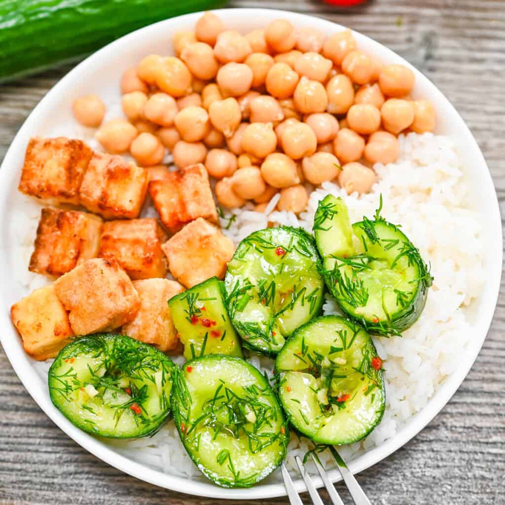 Marinated cucumbers served in a rice bowl with tofu and chickpeas