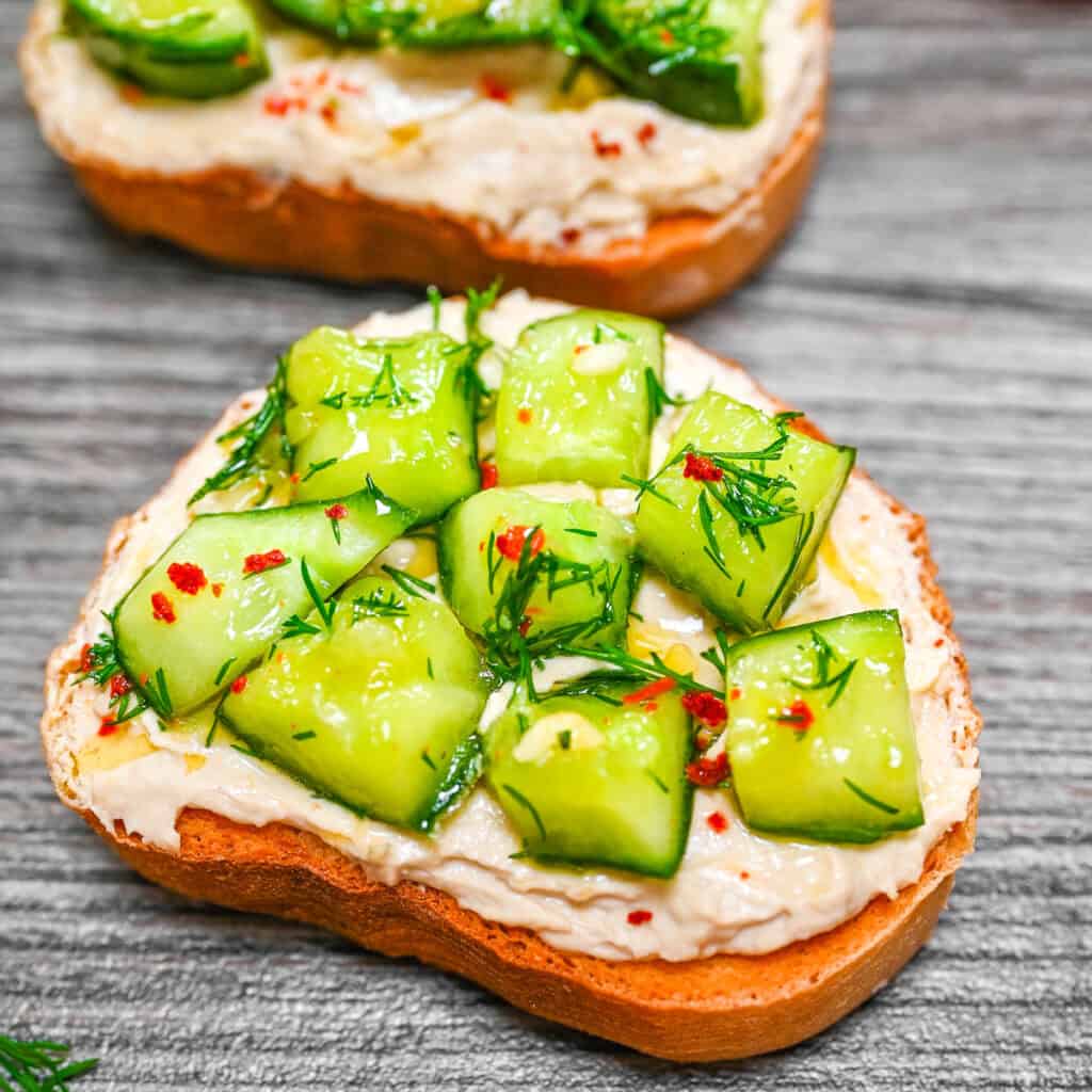 Marinated cucumbers on hummus toast