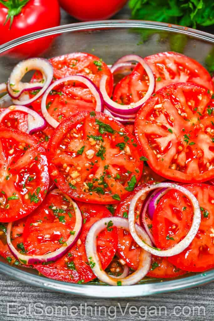 Marinated Tomatoes in a glass container with onion and herbs