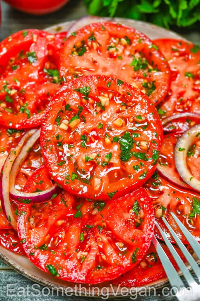 Marinated Tomatoes with onion and herbs, close-up with a fork