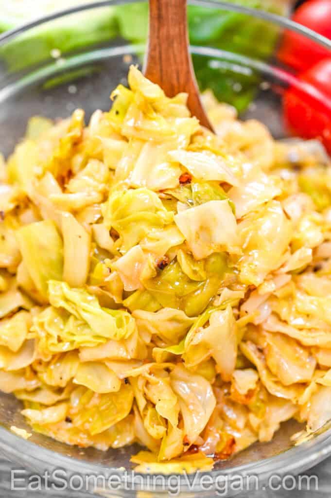Roasted cabbage salad in a glass bowl with wooden spoon