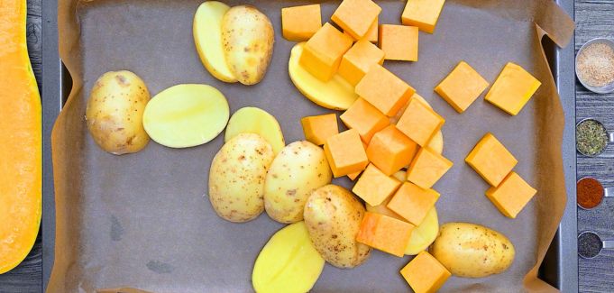Chopped potatoes and squash on a baking sheet