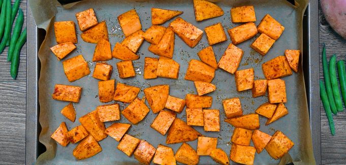 Seasoned sweet potato cubes on a baking sheet