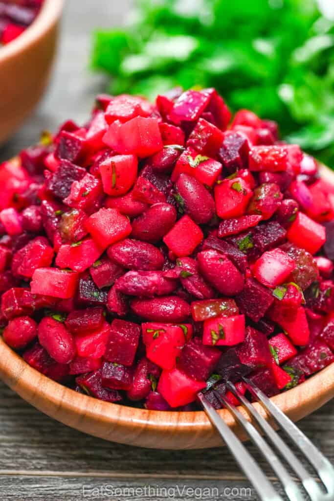 Beet and bean salad in a wooden bowl with a fork
