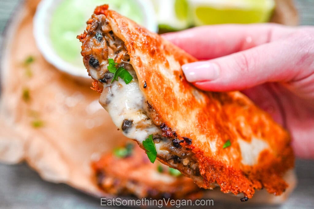Close up of crispy taco with cheesy mushroom filling
