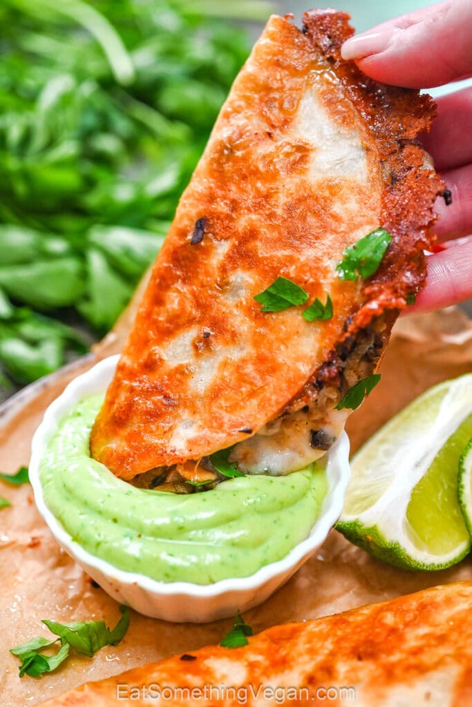 Dipping crispy taco into green sauce