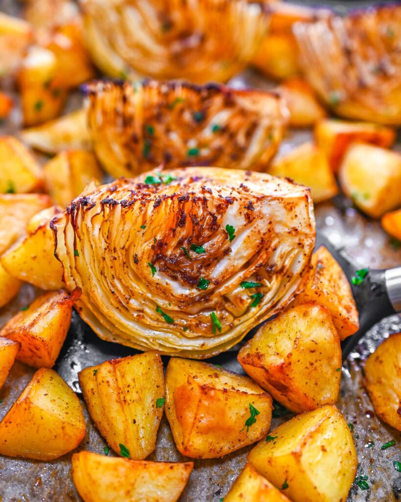 Roasted cabbage wedge with golden roasted potatoes on a baking sheet