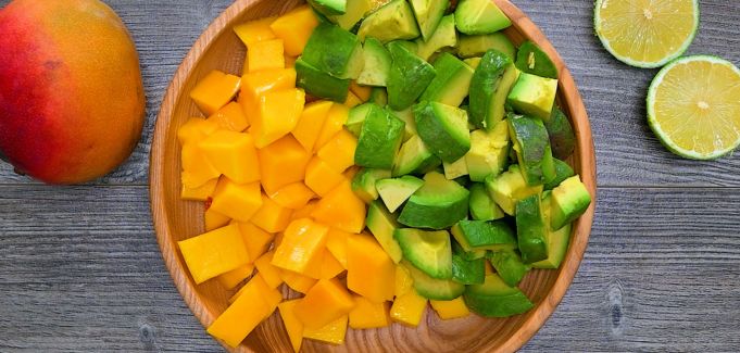 Diced mango and avocado on a wooden plate.
