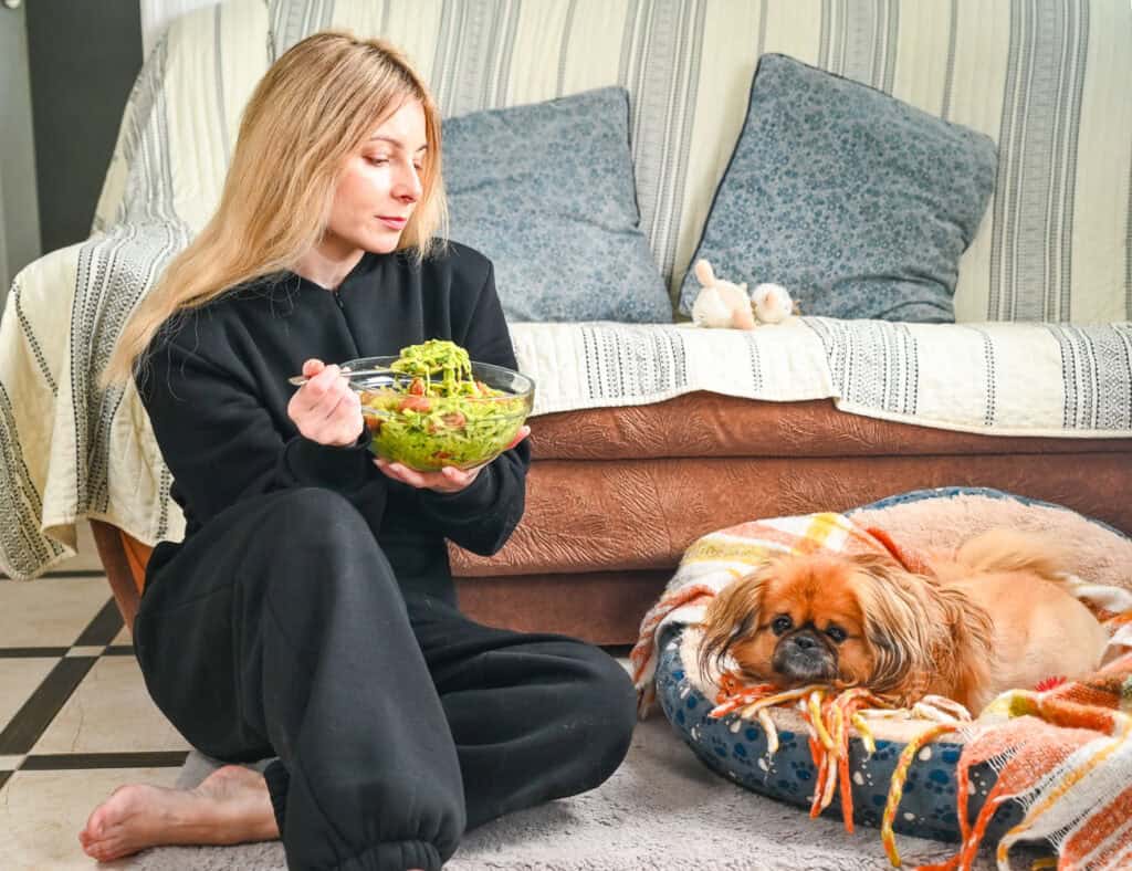 Woman enjoying a salad at home with her dog