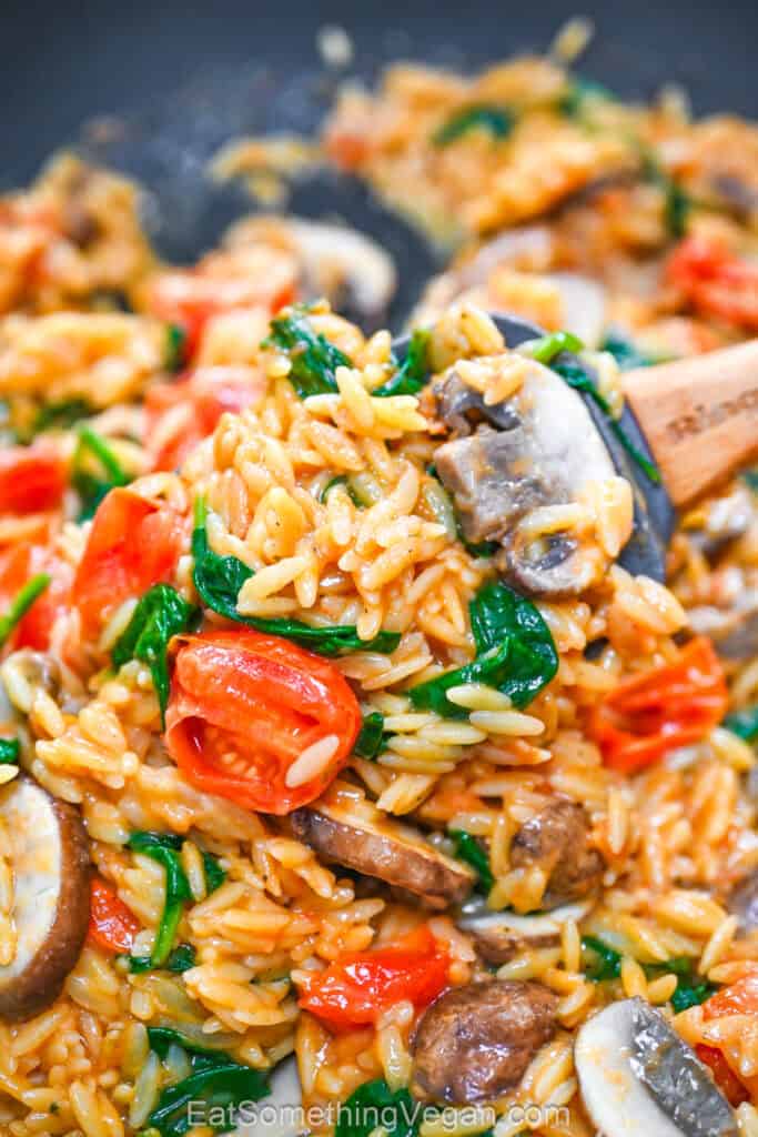 Creamy one-pan orzo with mushrooms, spinach, and cherry tomatoes on a spoon