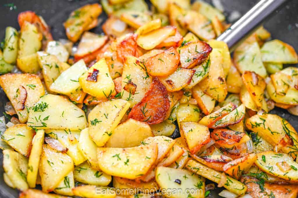 Crispy fried potato slices with onion and fresh dill in a skillet