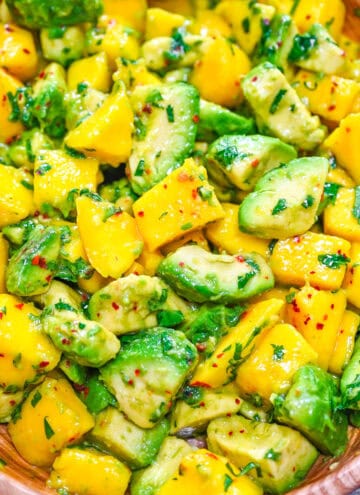 Mango avocado salad with cilantro and lime in a wooden bowl.