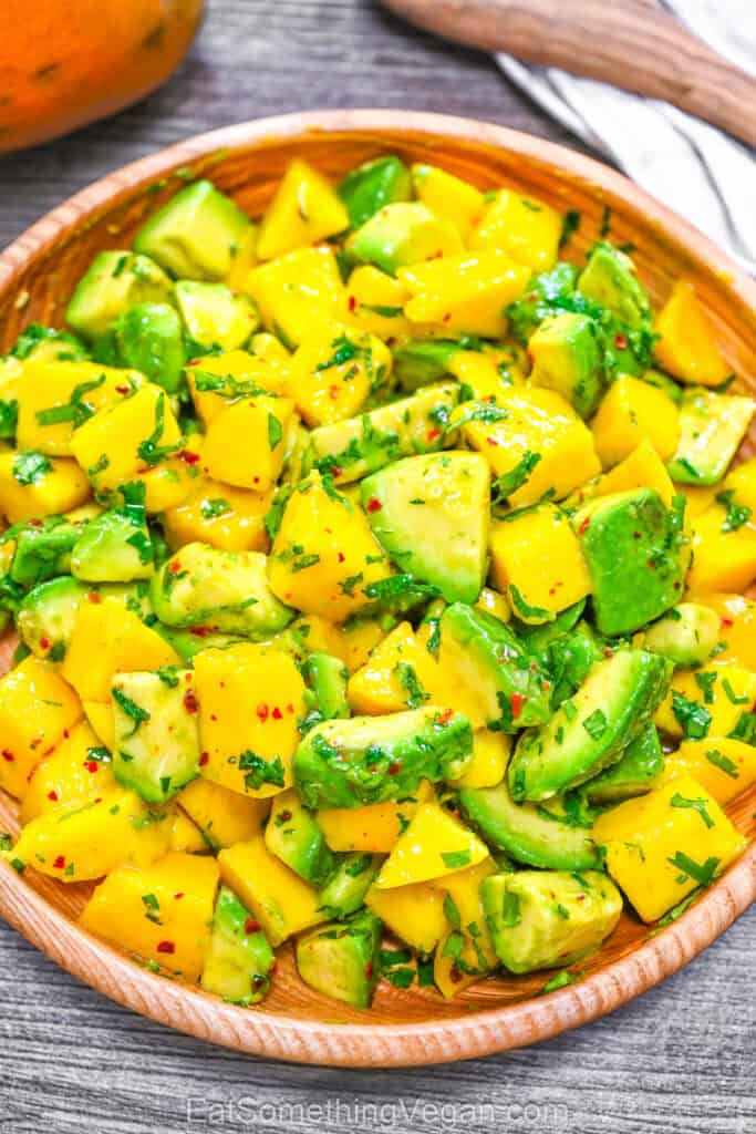 Fresh mango and avocado in a wooden bowl.