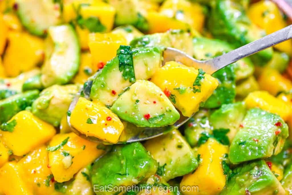 Spoonful of fresh fruit salad with cilantro.