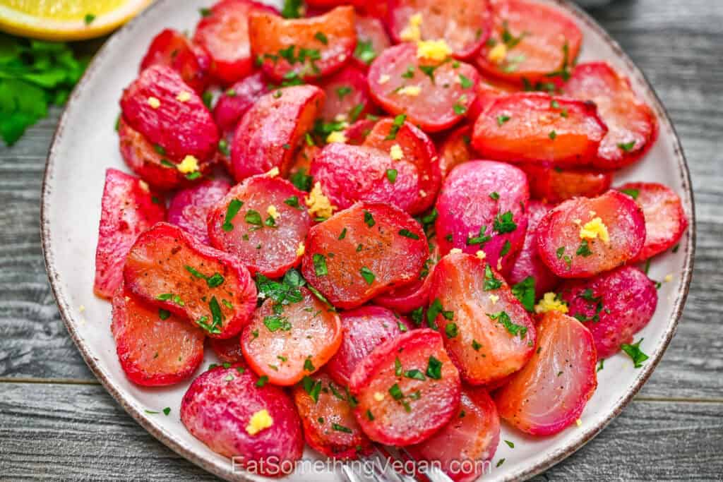 Roasted radishes garnished with fresh parsley and lemon zest on a white plate.