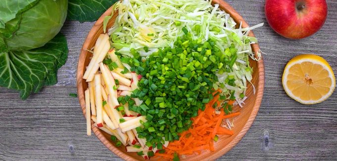 Shredded cabbage, apple, carrot, and green onions in a mixing bowl