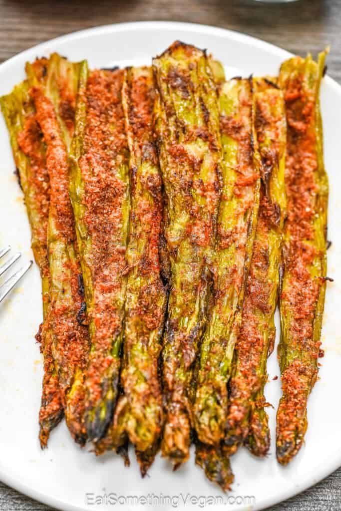 Roasted smashed asparagus side dish with a crispy garlic and paprika crust on a white plate.