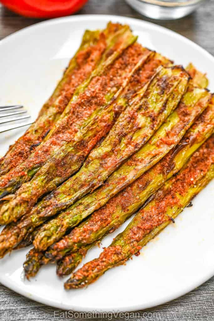 A serving of crispy smashed asparagus with golden seasoning on a white plate, ready to eat.