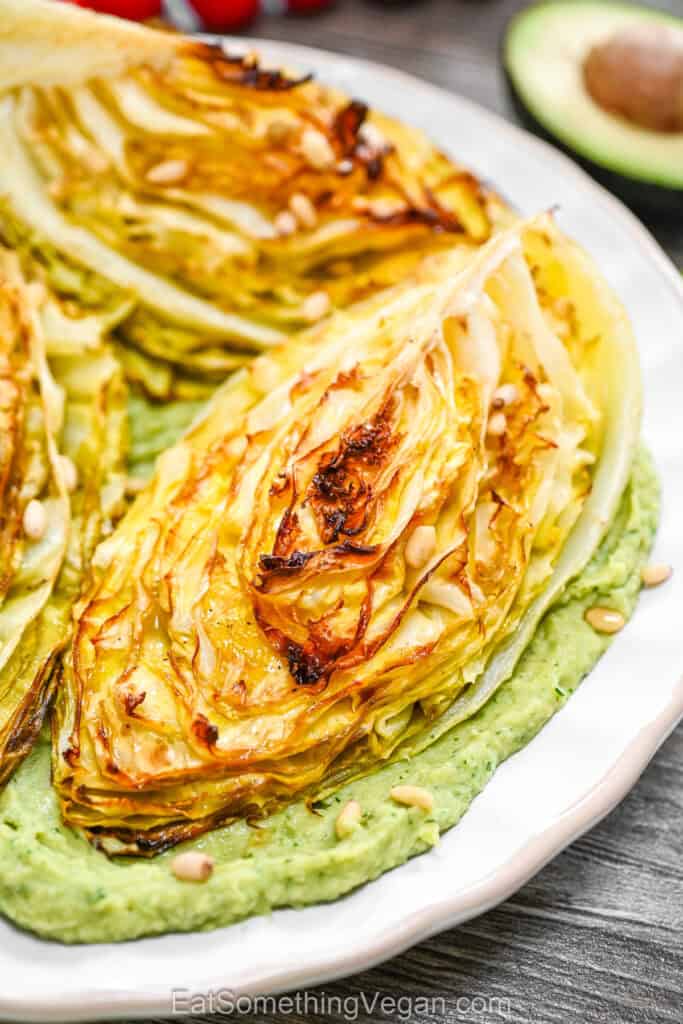 Golden charred cabbage wedges served over a smooth avocado and herb base.