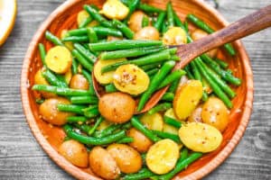 Warm Potato and Green Bean Salad featuring a vibrant mix of tender baby potatoes and crisp green beans in a zesty mustard dressing, served in a wooden bowl.