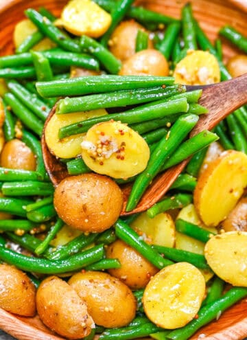 Warm Potato and Green Bean Salad featuring a vibrant mix of tender baby potatoes and crisp green beans in a zesty mustard dressing, served in a wooden bowl.