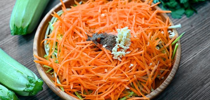 Adding garlic and seasonings to the zucchini and carrots.