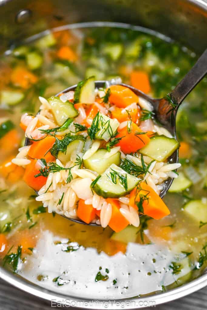 Cucumber Orzo Soup being scooped from a pot with a metal ladle.