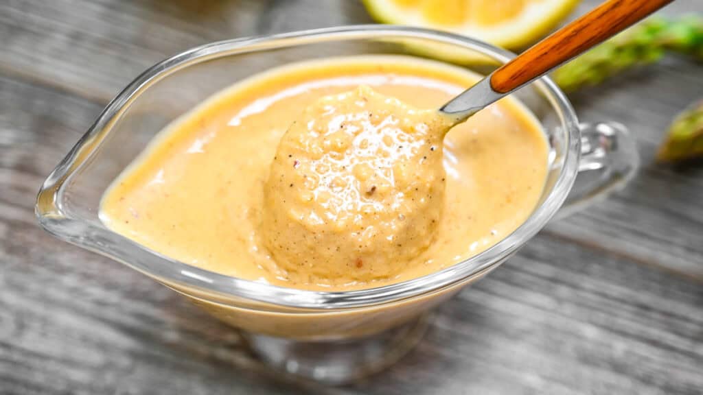 Creamy Fried Lemon Sauce in a glass gravy boat with a spoon.