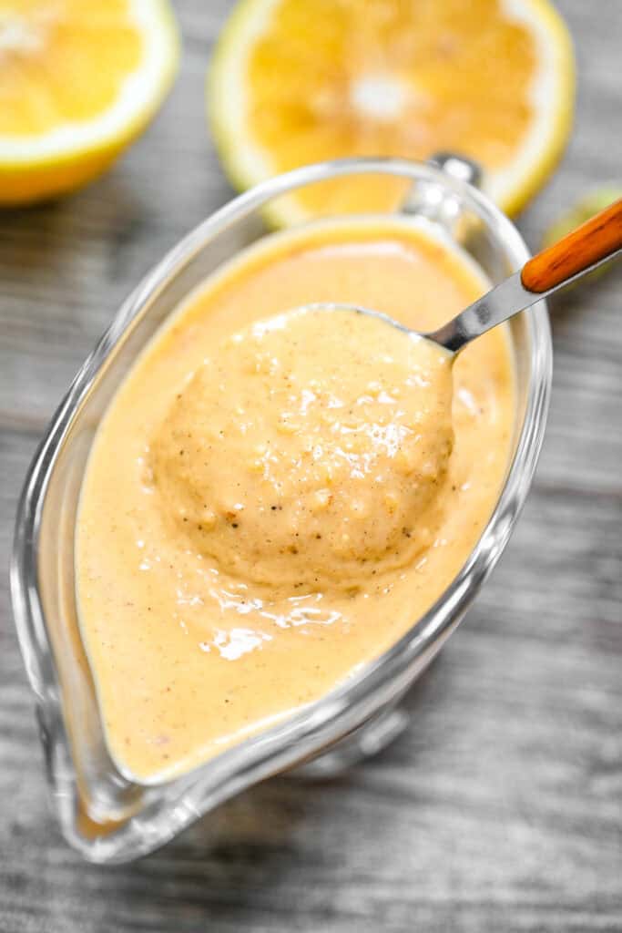 Fried lemon sauce in a glass gravy boat with a spoon.