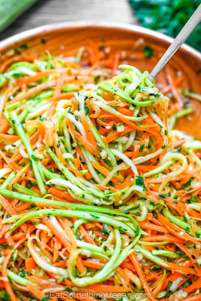 Korean-Style Zucchini Salad on a fork above a bowl.