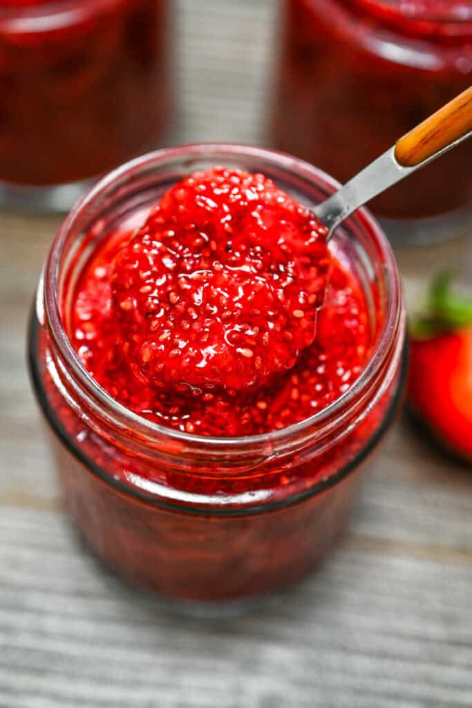 3-Ingredient Strawberry Chia Jam being scooped with a spoon from a glass jar.