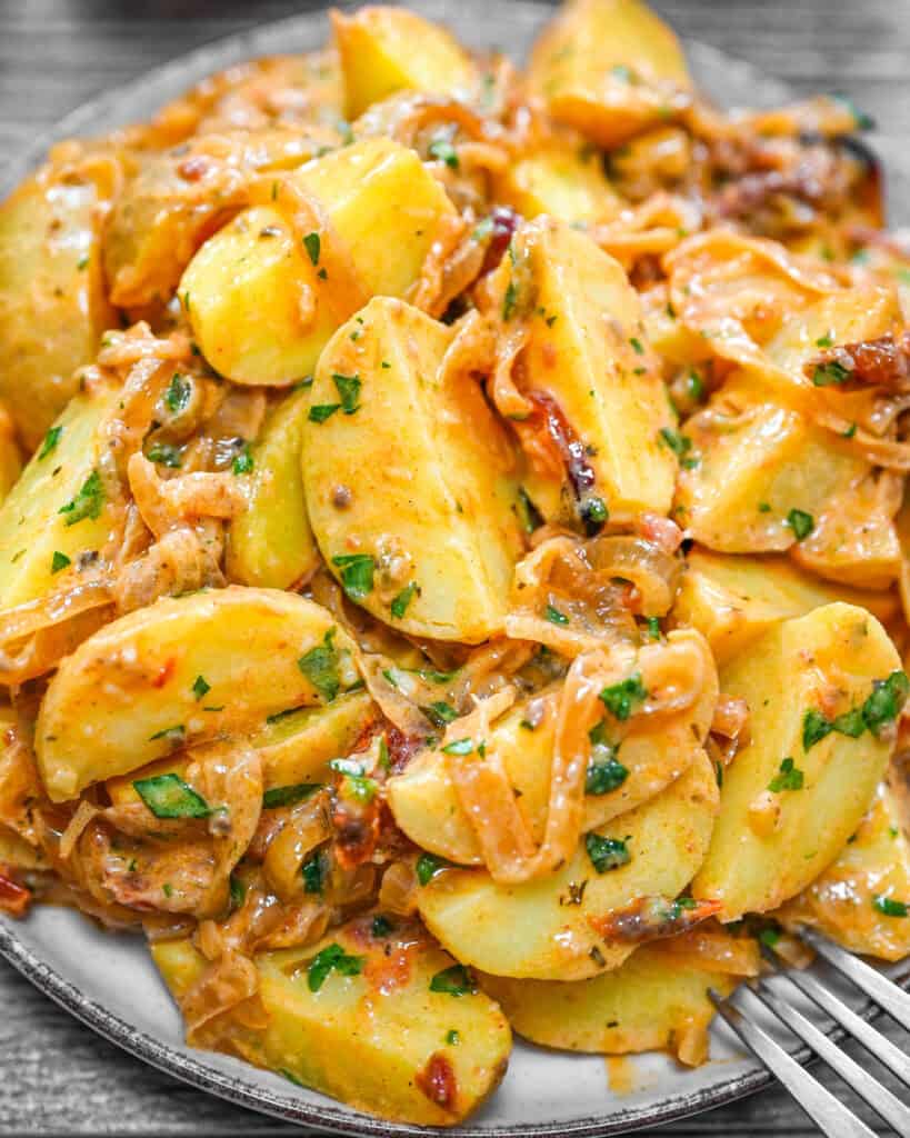 Caramelized onion potatoes served on a plate with a fork.