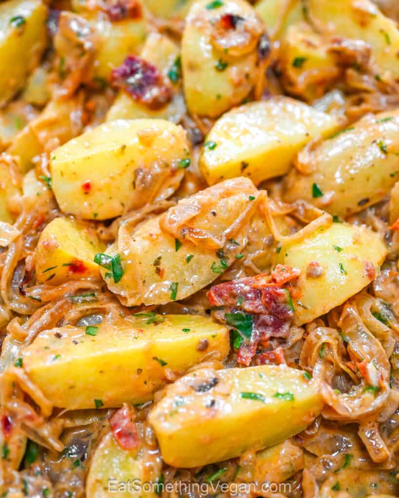 Caramelized onion potatoes close up with fresh herbs.