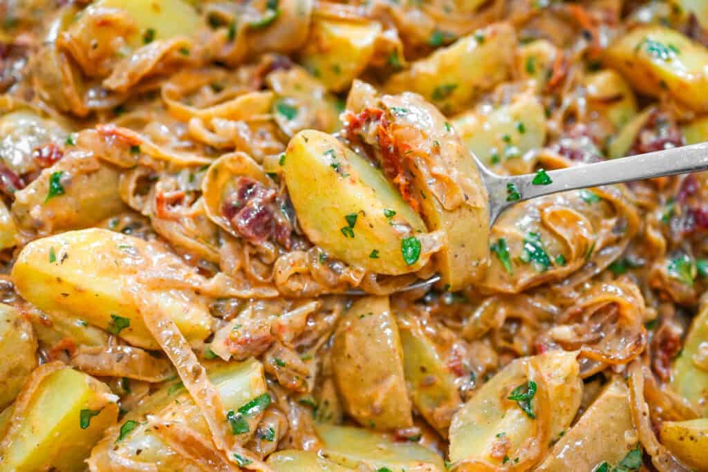 Creamy caramelized onion potatoes on a spoon.