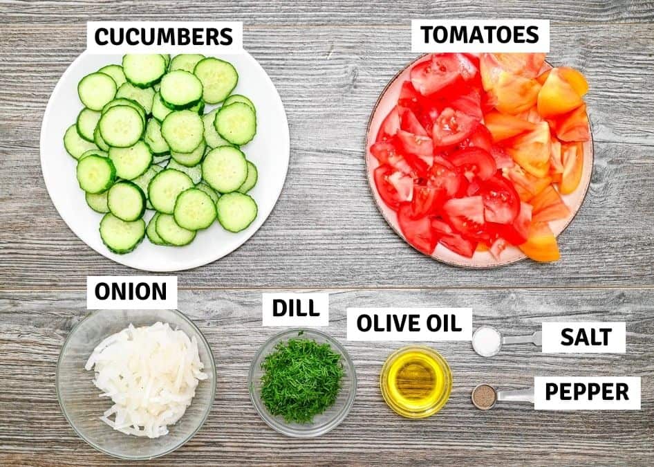 Fresh ingredients laid out on a wooden table with text labels, including sliced cucumbers, chopped tomatoes, sliced onions, fresh chopped dill, olive oil, salt, and pepper.