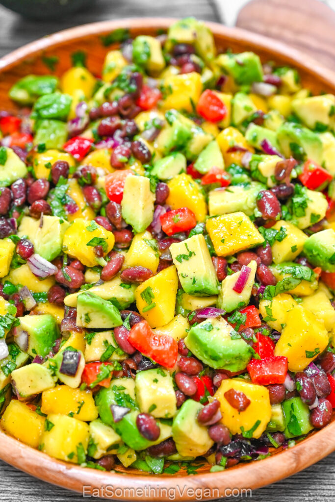 Salad with diced mango, avocado, and black beans in a wooden bowl.