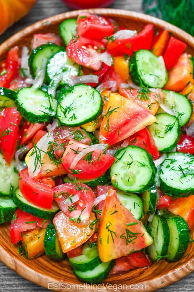 Cucumber Tomato Salad served in a rustic wooden bowl, showing a colorful mix of fresh cucumbers, tomatoes, onions, and dill.