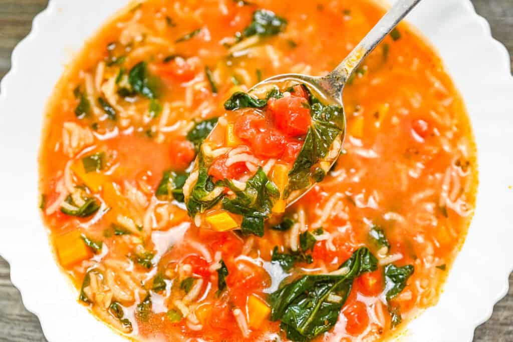 Tomato Spinach Rice Soup, a spoonful of hearty soup served in a white bowl.