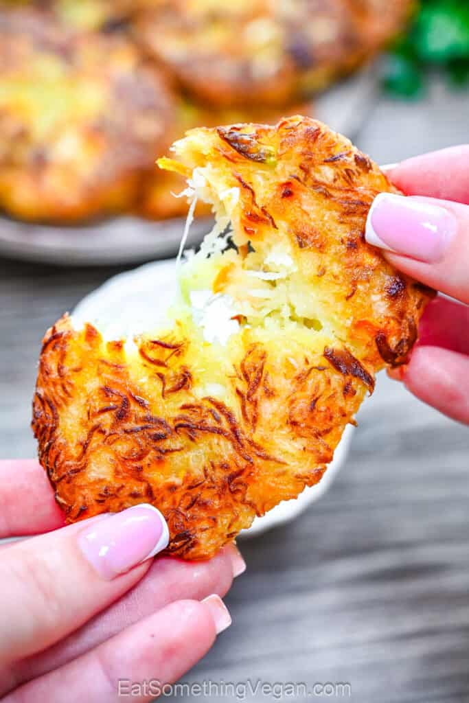 A golden brown crispy cabbage fritter is pulled apart, revealing the soft shredded cabbage inside.