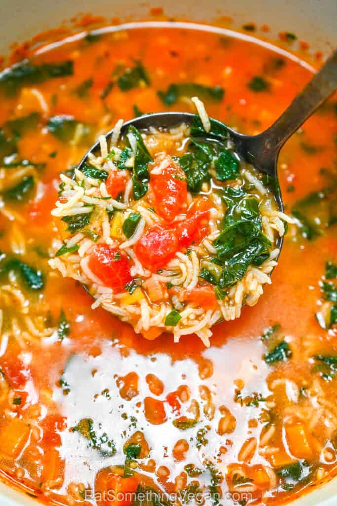 Tomato Spinach Rice Soup, a ladle full of soup above the pot.