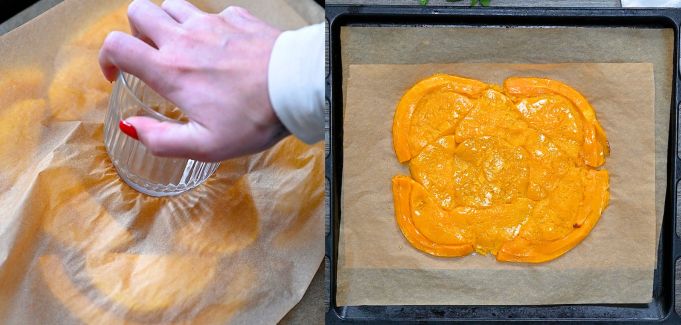 Flattening cooked butternut squash pieces on a baking tray with a glass through parchment paper.