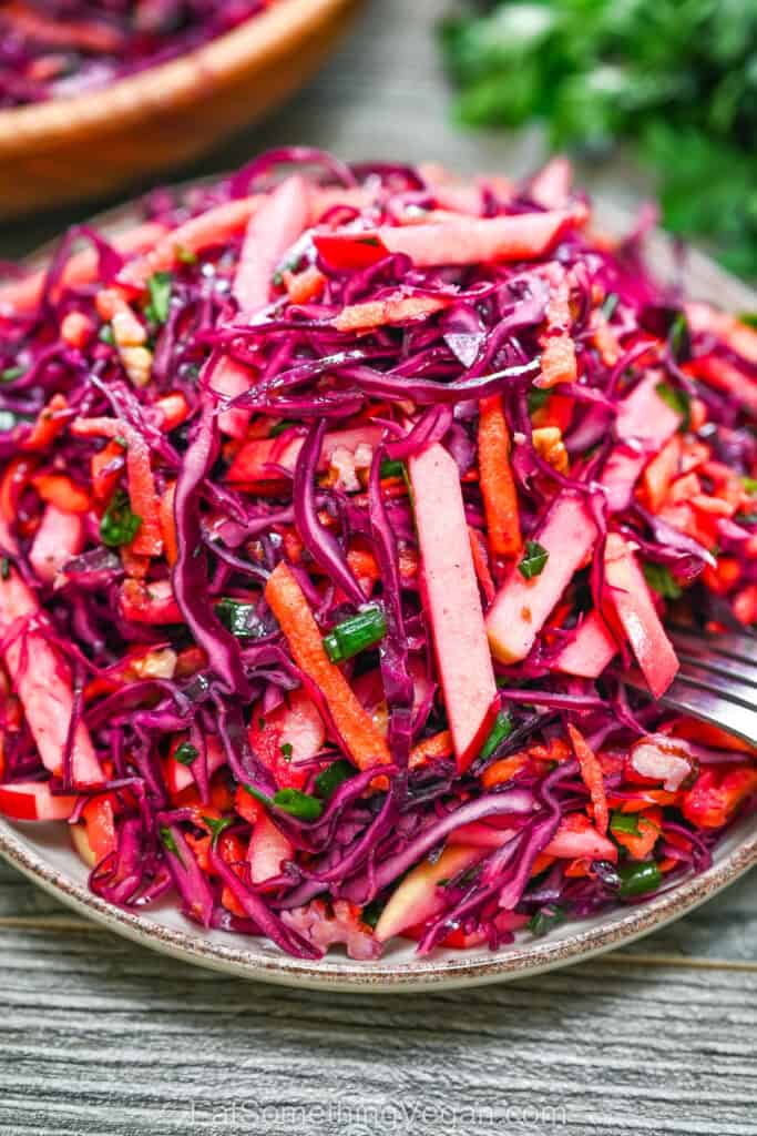 Red Cabbage Salad with Apples and Walnuts served on a ceramic plate with a fork.