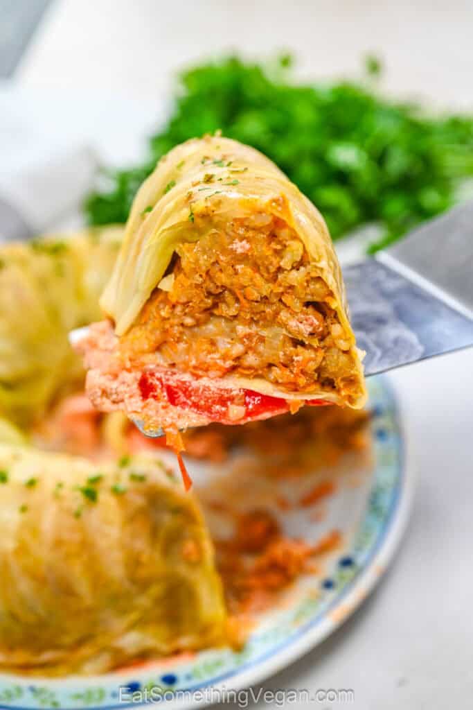A slice of Bundt pan cabbage roll cake lifted on a spatula, showing the tender cabbage leaves and savory rice filling inside